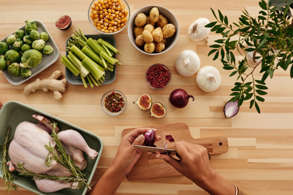 A vibrant flat lay of fresh ingredients with hands preparing vegetables for a healthy meal.
