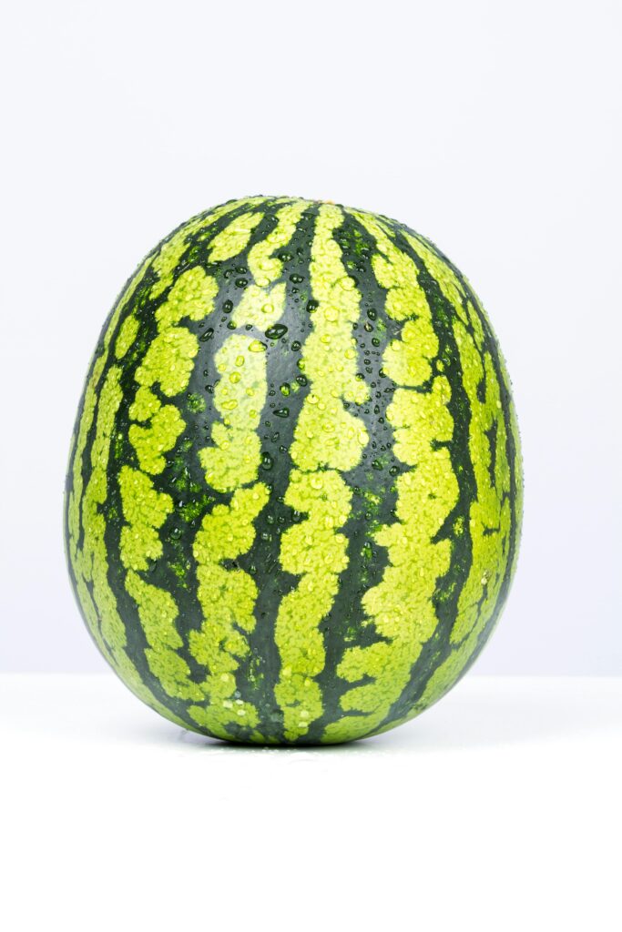 High-quality image of a fresh green watermelon with water droplets on a white background.