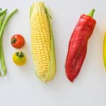 A vibrant assortment of fresh vegetables including corn, peppers, beans, and tomatoes.