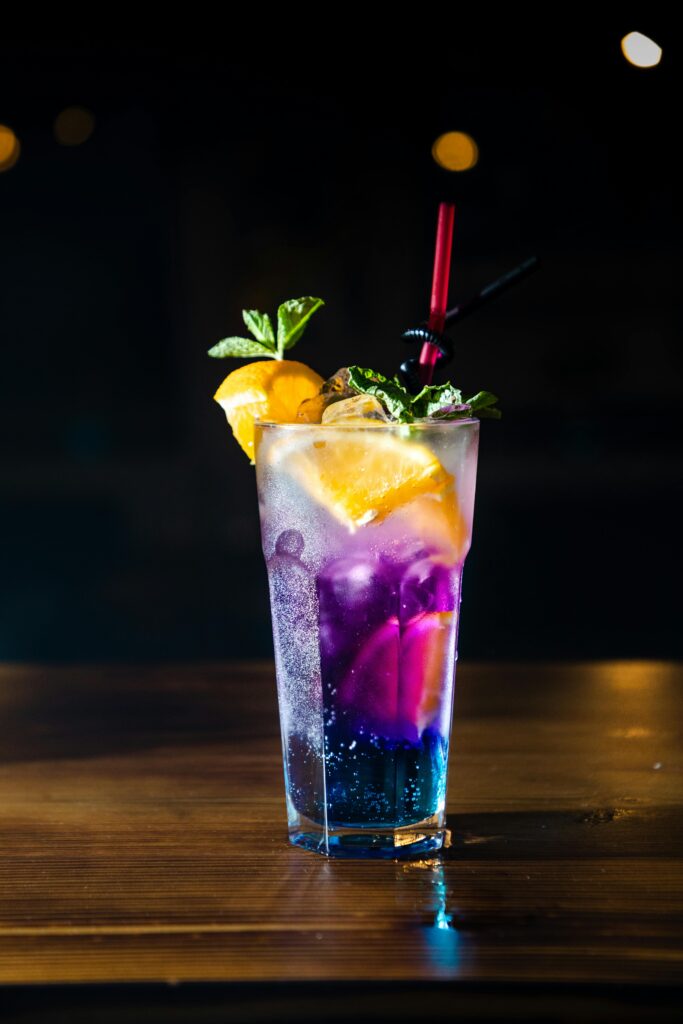 A colorful cocktail with citrus garnish on a table, perfect for nightlife or social gatherings.
