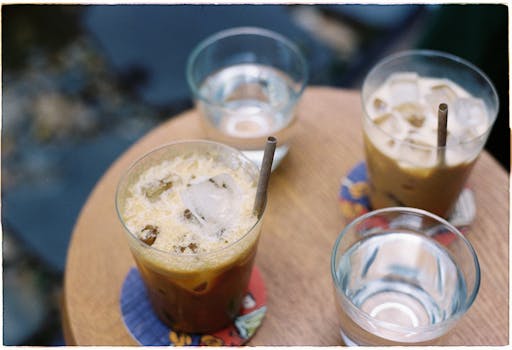 Top view of Vietnamese iced coffee and water glasses on a wooden table outdoors.